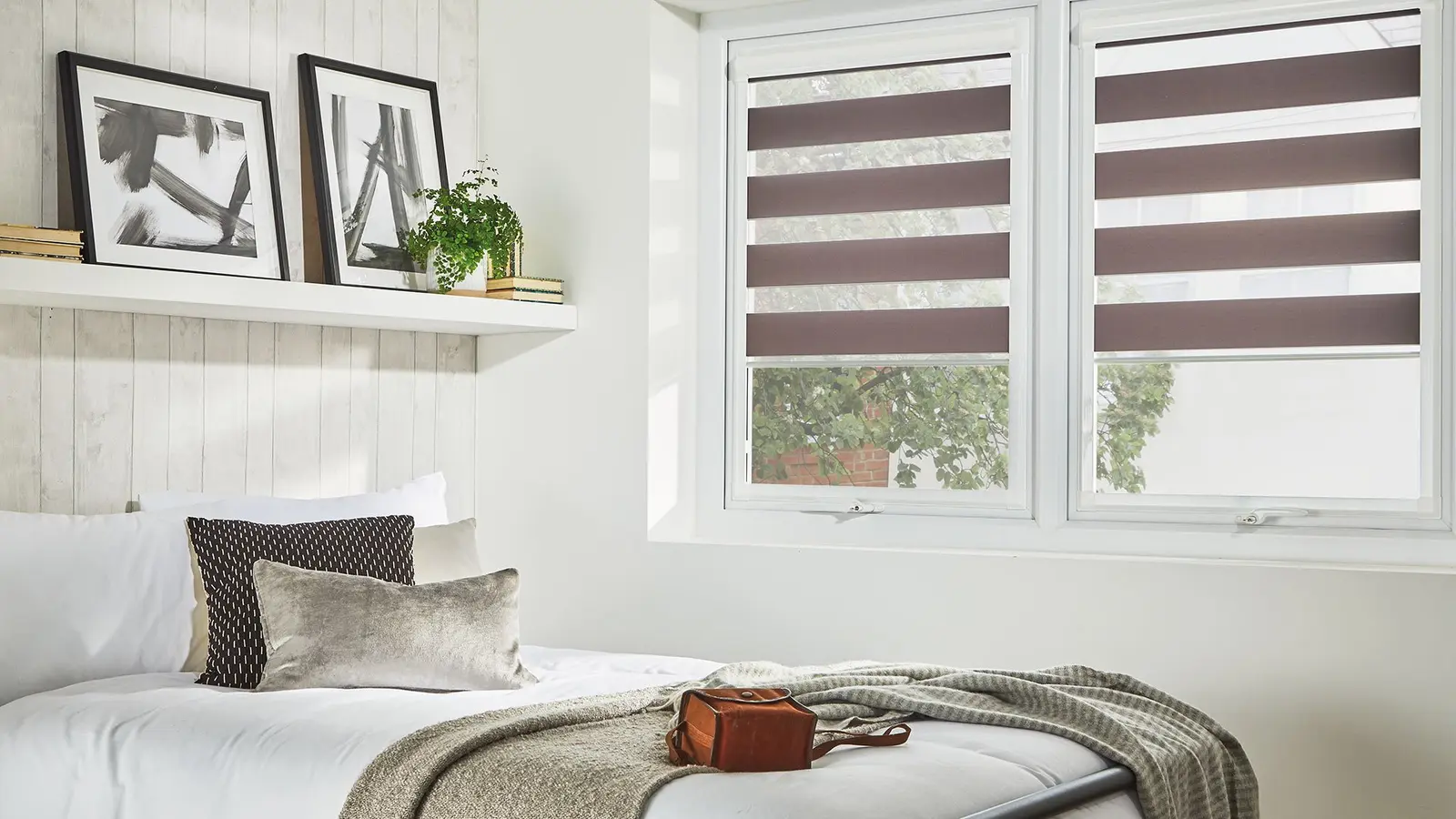 Striped blinds fitted inside two uPVC window frames in a bedroom, clear of the sill