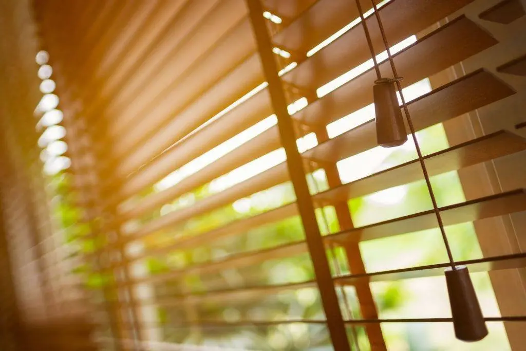 Real wood venetian blinds with wide slats on a bay window